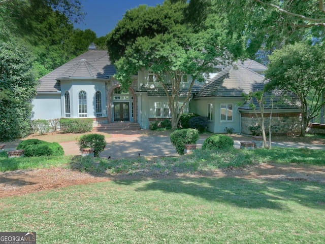 view of front of home featuring stucco siding, a front lawn, and french doors