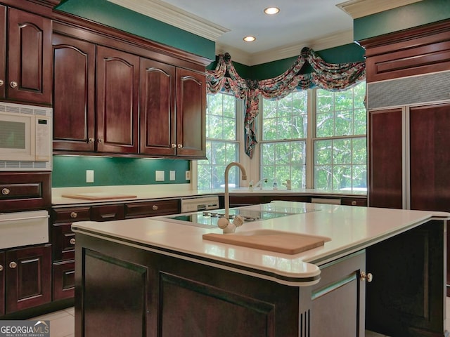kitchen with built in appliances, light countertops, a kitchen island with sink, and a warming drawer