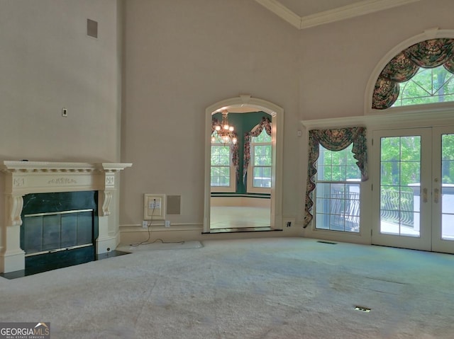 unfurnished living room with carpet floors, crown molding, french doors, and a chandelier