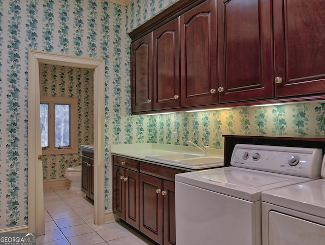 washroom featuring a sink, wallpapered walls, light tile patterned flooring, cabinet space, and washing machine and dryer