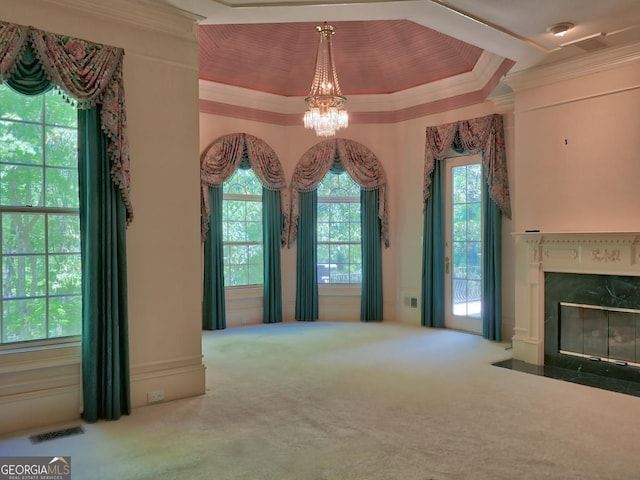 unfurnished living room featuring carpet flooring, visible vents, an inviting chandelier, a premium fireplace, and ornamental molding