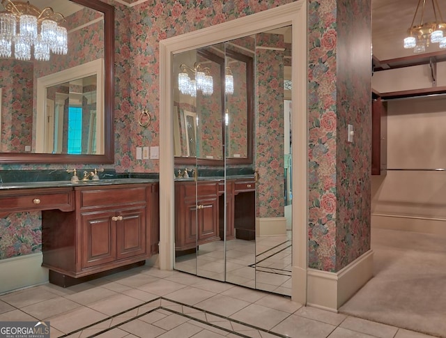 bathroom with a chandelier, wallpapered walls, tile patterned floors, and vanity