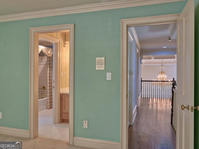 corridor with baseboards, a notable chandelier, and crown molding