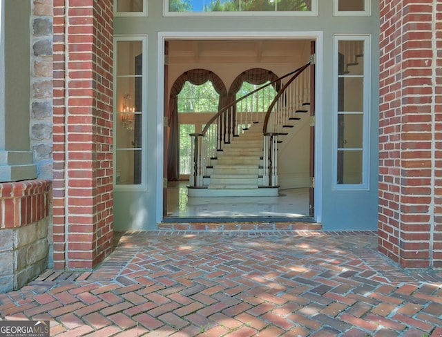 view of exterior entry with stucco siding and brick siding