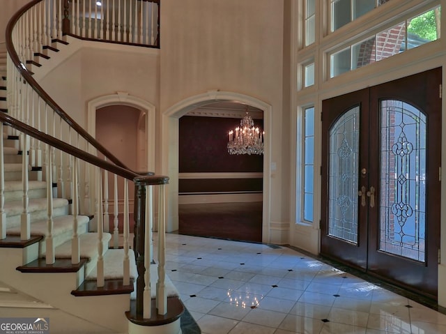 tiled entrance foyer with a towering ceiling, stairs, and french doors