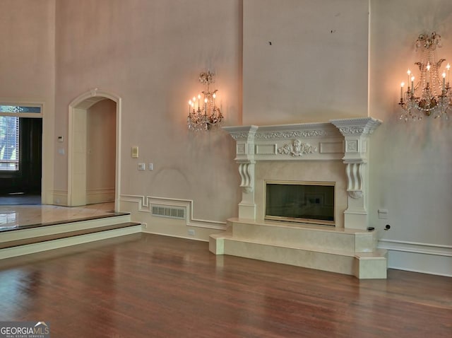 unfurnished living room with arched walkways, a high ceiling, and a notable chandelier