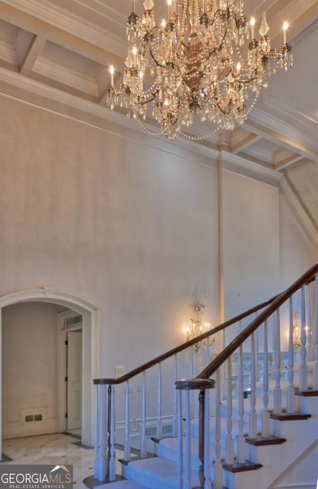 stairway featuring arched walkways, coffered ceiling, a notable chandelier, and a high ceiling