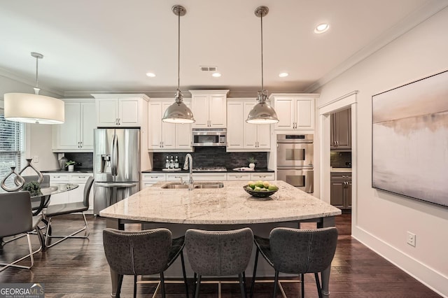 3699 School St, Chamblee, GA 30341 - kitchen with stainless steel appliances, ornamental molding, tasteful backsplash, a center island with sink, and white cabinetry