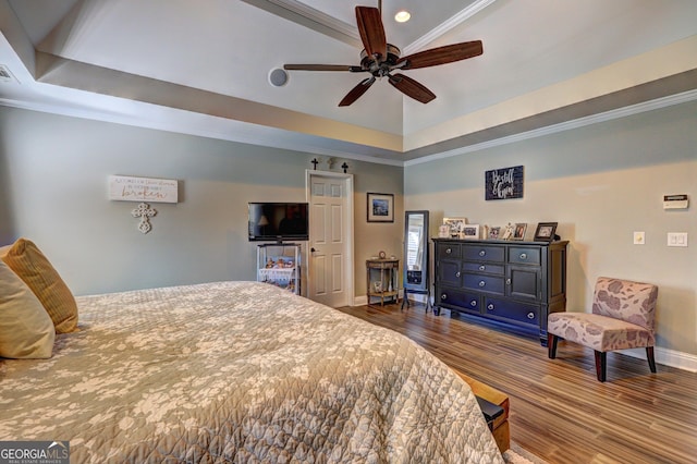bedroom with baseboards, a raised ceiling, wood finished floors, and crown molding