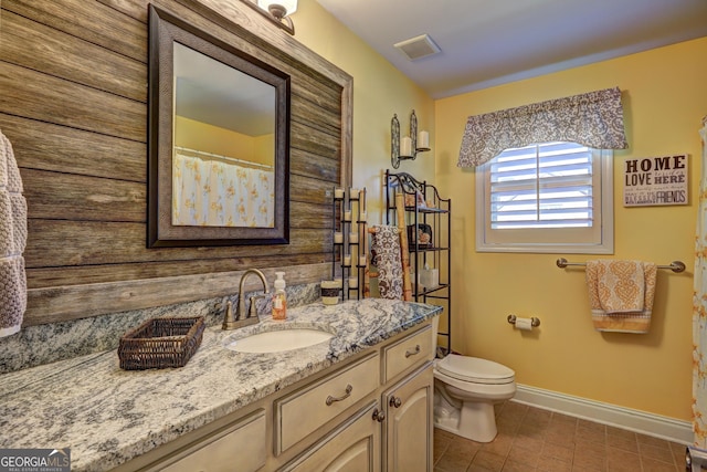 bathroom with tile patterned flooring, toilet, vanity, baseboards, and visible vents