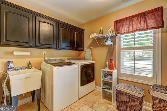 clothes washing area featuring baseboards, cabinet space, washer and clothes dryer, and a sink