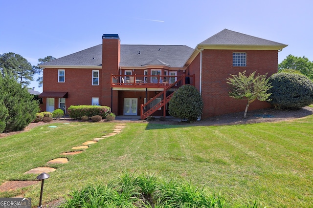 back of property with a yard, a chimney, brick siding, a deck, and french doors