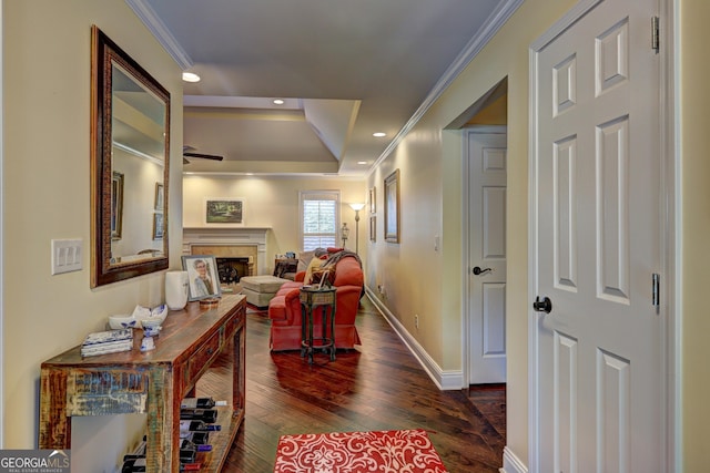 hall with baseboards, recessed lighting, dark wood-style floors, crown molding, and a tray ceiling