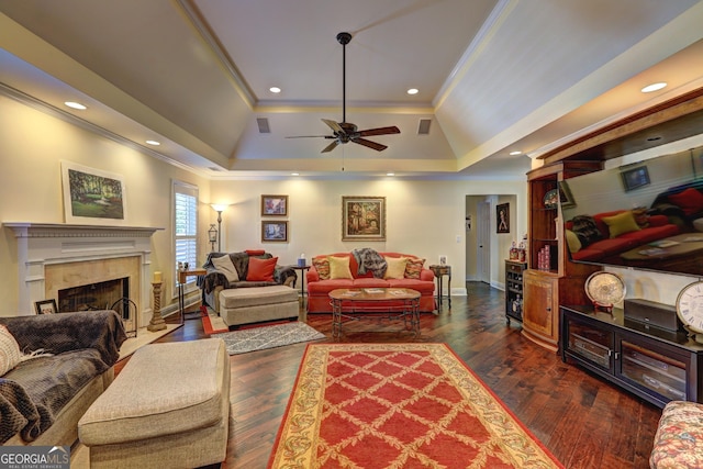 living area featuring a tray ceiling, dark wood-style floors, baseboards, ornamental molding, and a premium fireplace
