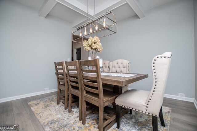 dining area featuring beam ceiling, wood finished floors, baseboards, and a chandelier