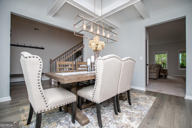 dining room featuring a chandelier, beamed ceiling, wood finished floors, and baseboards