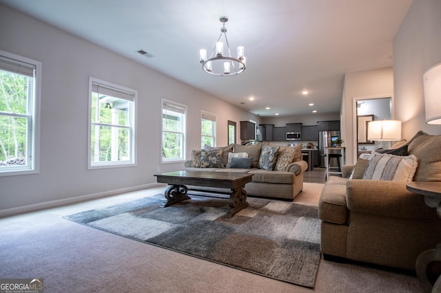 living area featuring a chandelier, light colored carpet, and baseboards