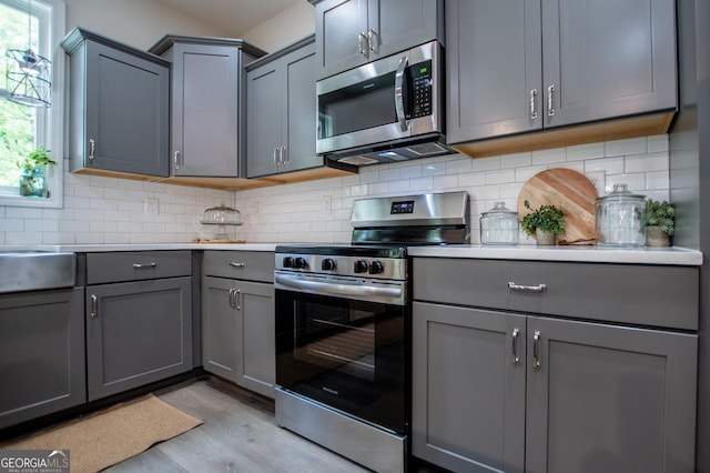 kitchen with stainless steel appliances, gray cabinets, light wood-style flooring, and plenty of natural light