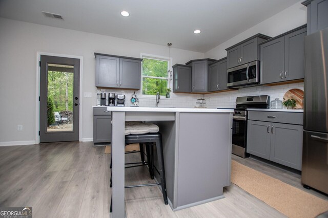 kitchen featuring stainless steel appliances, light wood-style floors, decorative backsplash, and recessed lighting
