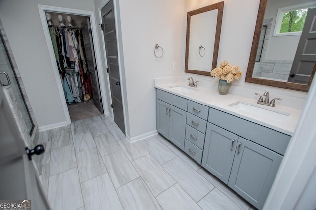 full bath with a walk in closet, baseboards, double vanity, and an enclosed shower