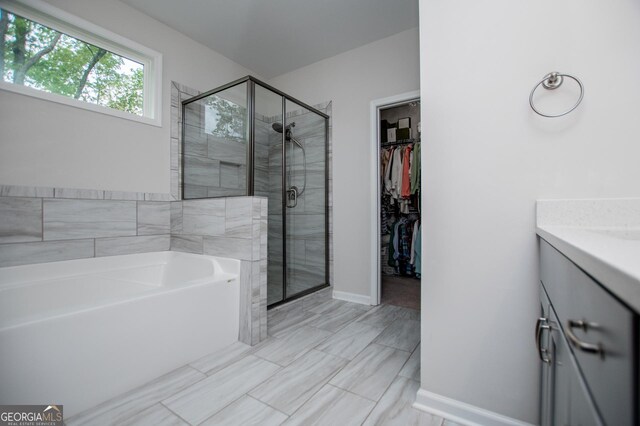full bath with a stall shower, a garden tub, vanity, and a spacious closet