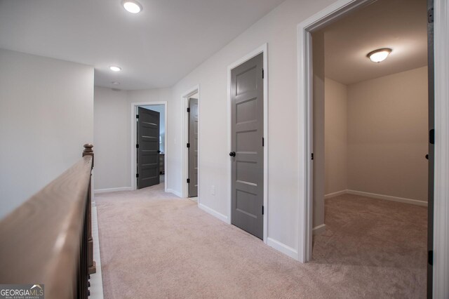 corridor featuring light carpet, baseboards, recessed lighting, and an upstairs landing