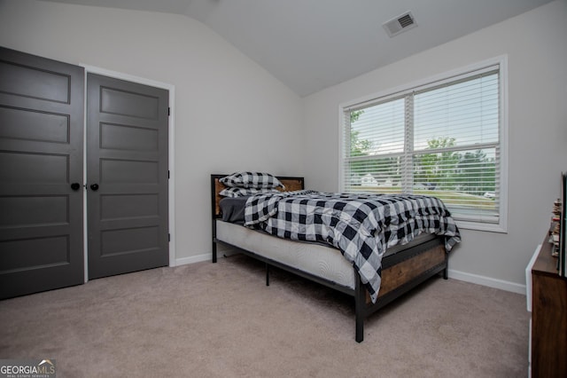 bedroom featuring lofted ceiling, light colored carpet, and baseboards