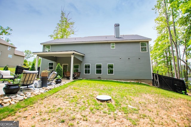rear view of house featuring a patio, a chimney, and a gate