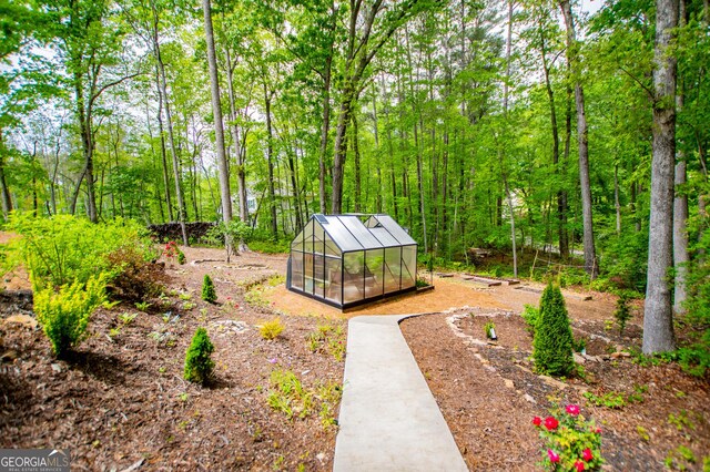 view of yard featuring a greenhouse and an outbuilding