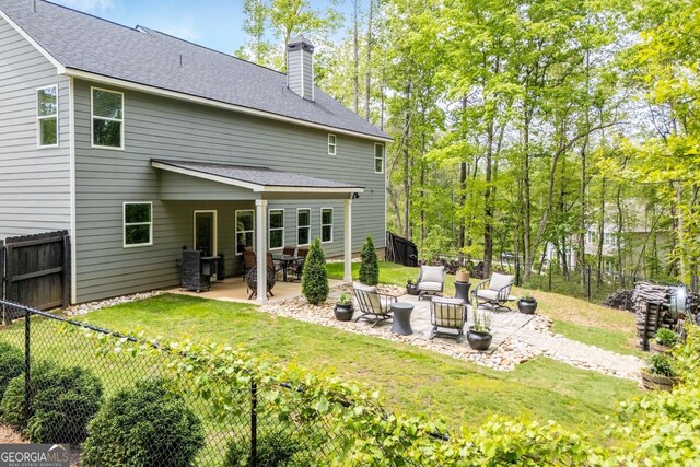 rear view of property with a patio area, a chimney, and roof with shingles