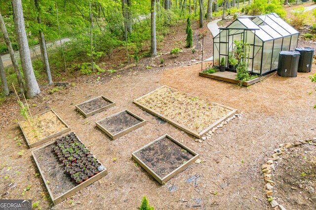 view of yard with a greenhouse, a garden, and an outdoor structure