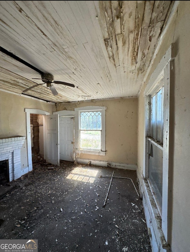 unfurnished living room with wood ceiling, a ceiling fan, and a fireplace