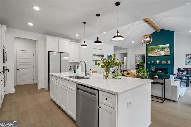 kitchen with white cabinets, stainless steel dishwasher, a sink, a center island with sink, and light wood-type flooring