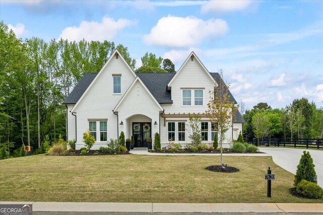 french country inspired facade with french doors, a front lawn, and fence