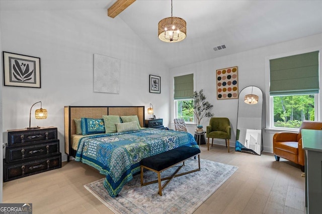 bedroom with beamed ceiling, wood finished floors, visible vents, and high vaulted ceiling