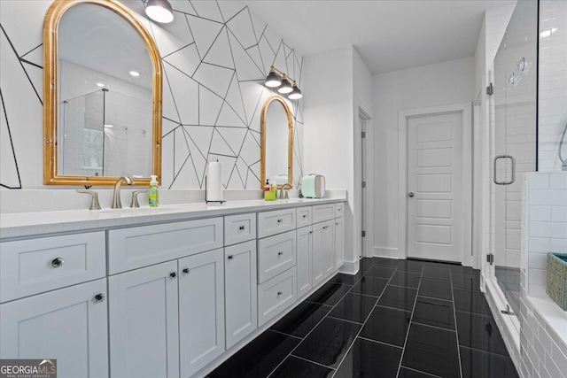 bathroom with tile patterned floors, a sink, a shower stall, and double vanity
