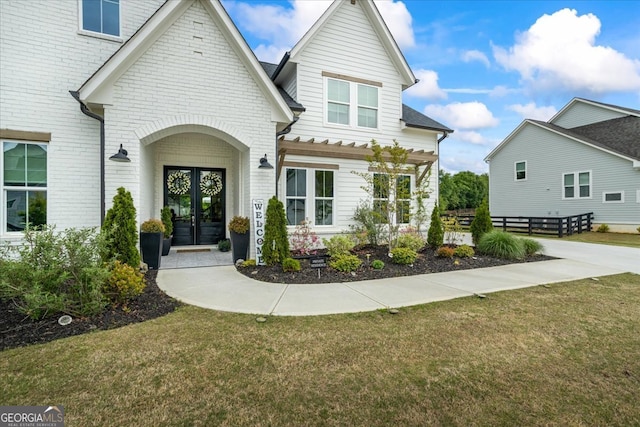 view of front of property with a front yard, french doors, and brick siding