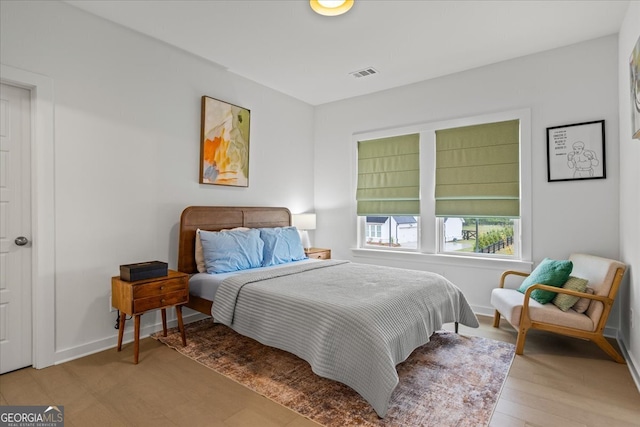 bedroom featuring wood finished floors, visible vents, and baseboards
