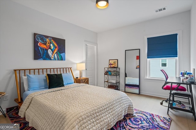 bedroom featuring baseboards, wood finished floors, and visible vents