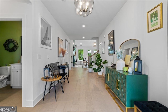 corridor featuring recessed lighting, light wood-style floors, baseboards, and an inviting chandelier