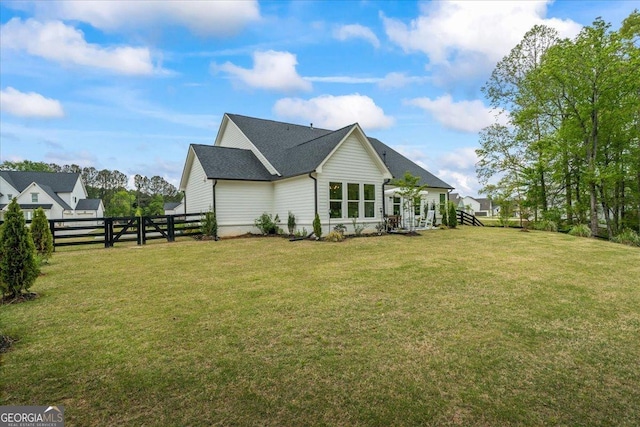 view of home's exterior featuring roof with shingles, fence, and a yard
