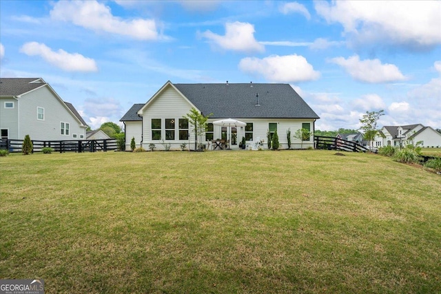 rear view of house featuring a shingled roof, a fenced backyard, and a yard