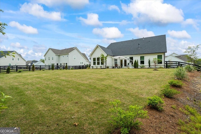 back of property with a fenced backyard, roof with shingles, and a yard