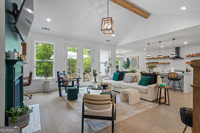 living area featuring recessed lighting, light wood finished floors, visible vents, beamed ceiling, and a chandelier