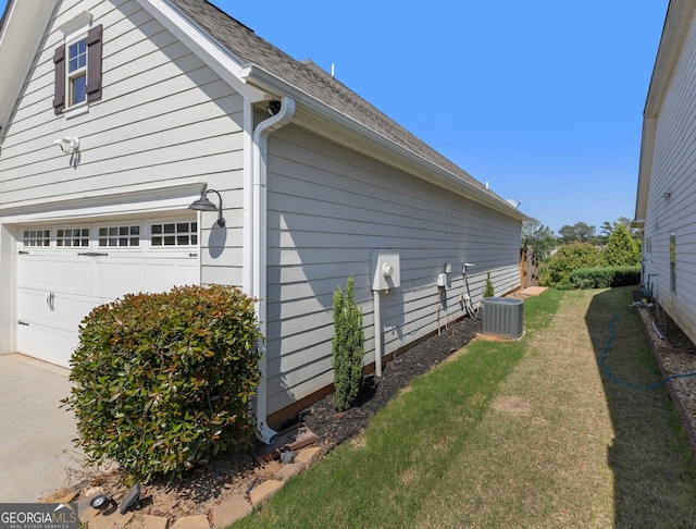 view of side of home with central air condition unit, a yard, and a garage