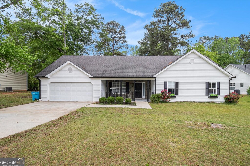 ranch-style house featuring central air condition unit, concrete driveway, covered porch, a front yard, and a garage