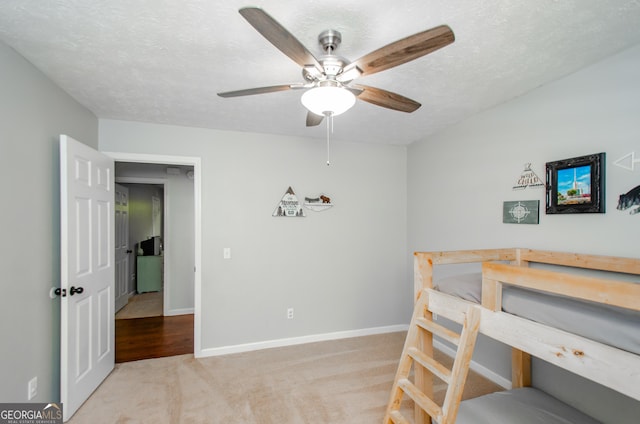 bedroom with ceiling fan, baseboards, carpet flooring, and a textured ceiling