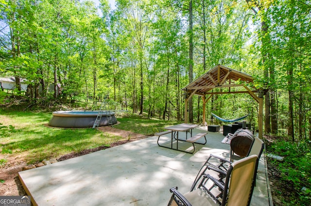 view of property's community featuring a gazebo, a swimming pool, a view of trees, a yard, and a patio