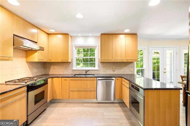 5655 Errol Pl NW, Atlanta, GA 30327 - kitchen featuring dark stone counters, a sink, under cabinet range hood, a peninsula, and appliances with stainless steel finishes