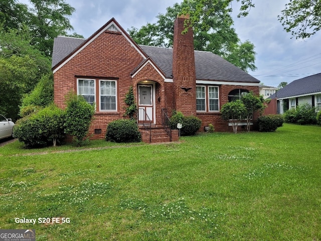 view of front of house with a front yard, roof with shingles, a chimney, brick siding, and crawl space